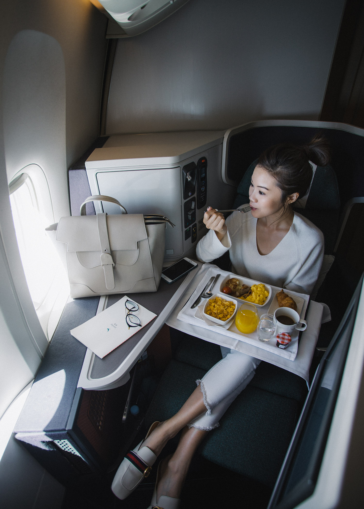 Fashion and travel blogger influencer Jenny Tsang of Tsangtastic traveling in Hong Kong, with Cathay Pacific in business class, wearing Vince Cashmere Off Shoulder Sweater and Gucci White Leather Slipper.