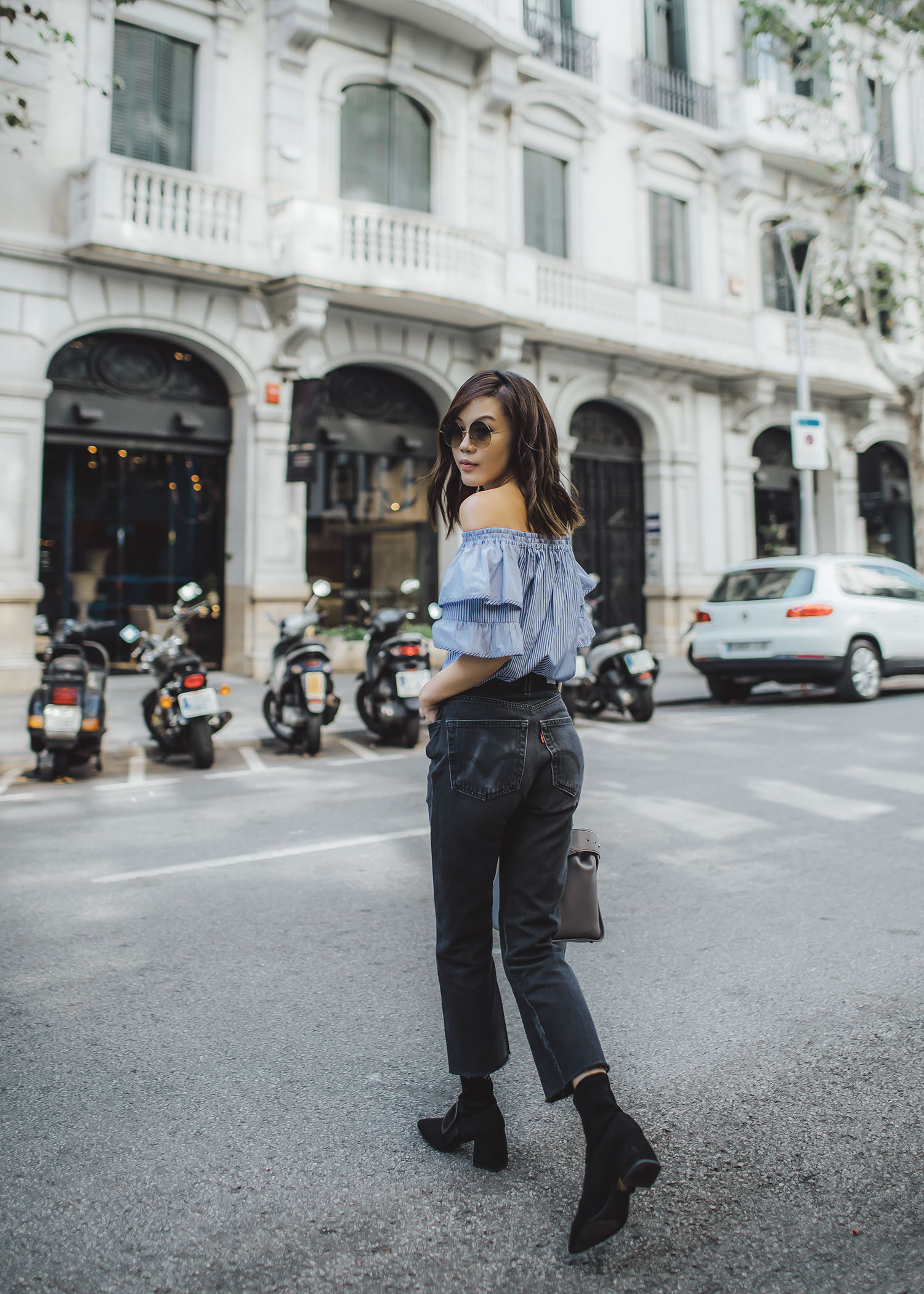 Lifestyle fashion travel blogger Jenny Tsang of Tsangtastic wearing off shoulder ruffle sleeve top and re/done levis jeans and roger vivier leather bag in Barcelona Spain.