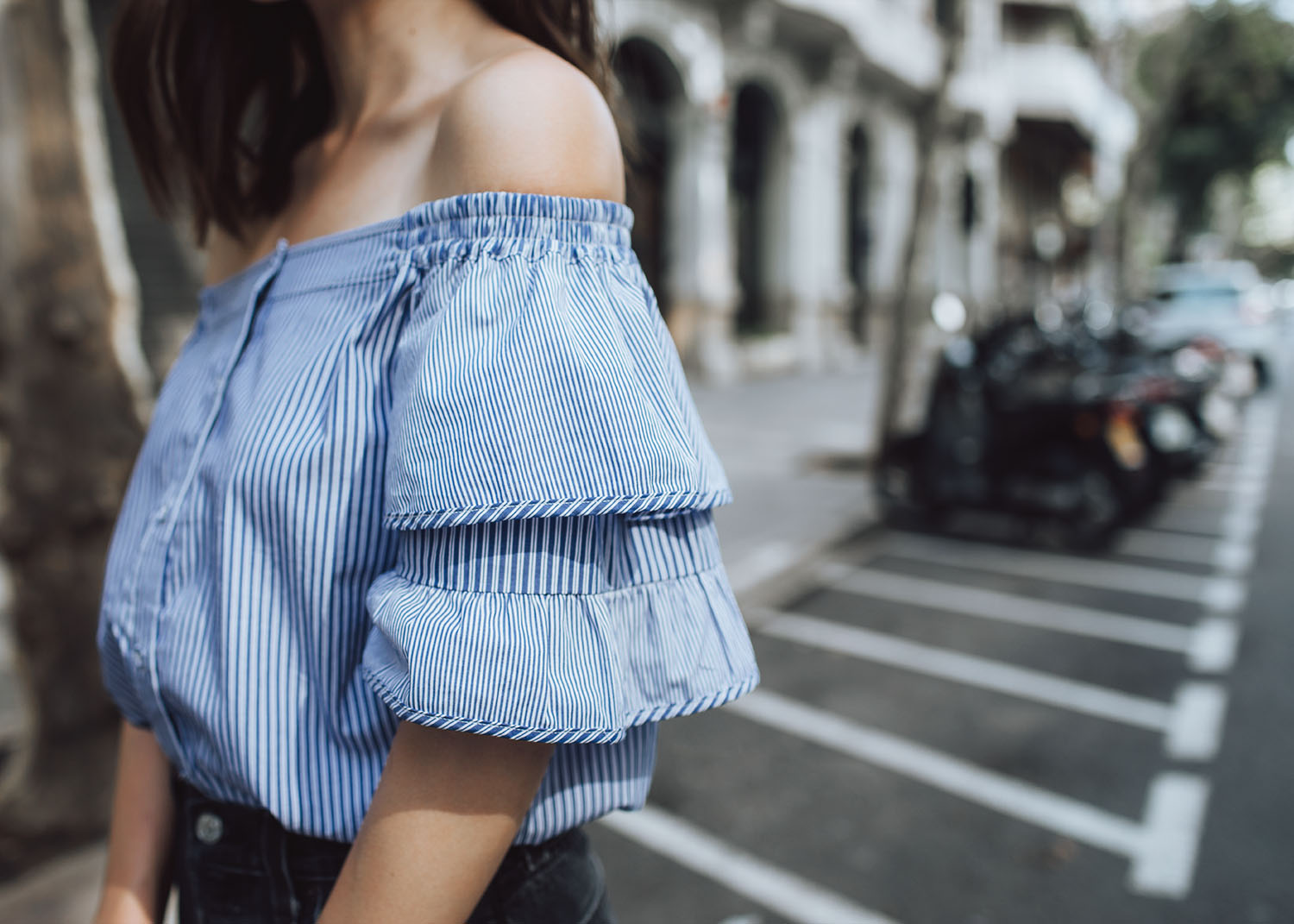 Lifestyle fashion travel blogger Jenny Tsang of Tsangtastic wearing off shoulder ruffle sleeve top and re/done levis jeans and roger vivier leather bag in Barcelona Spain.