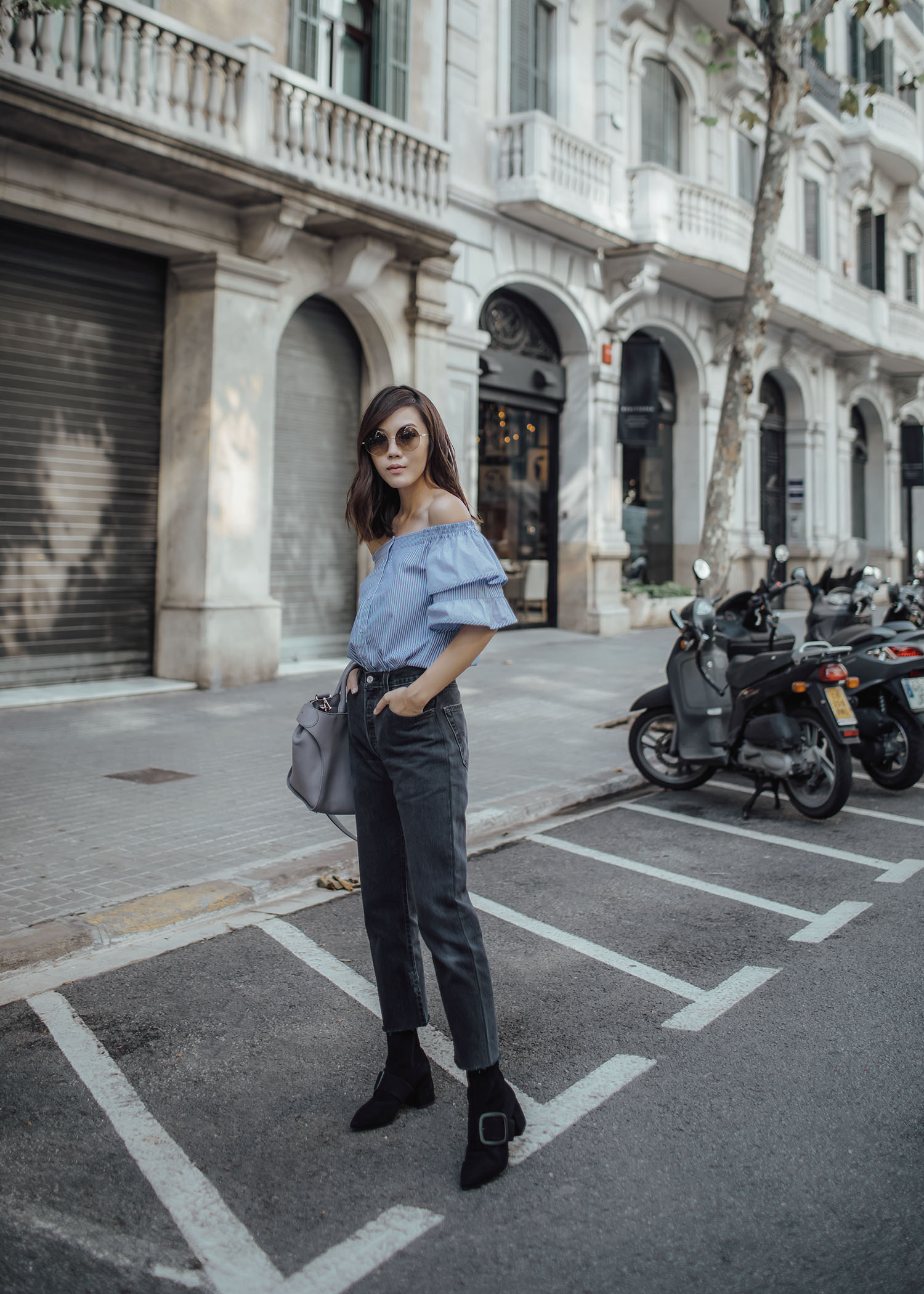 Lifestyle fashion travel blogger Jenny Tsang of Tsangtastic wearing off shoulder ruffle sleeve top and re/done levis jeans and roger vivier leather bag in Barcelona Spain.