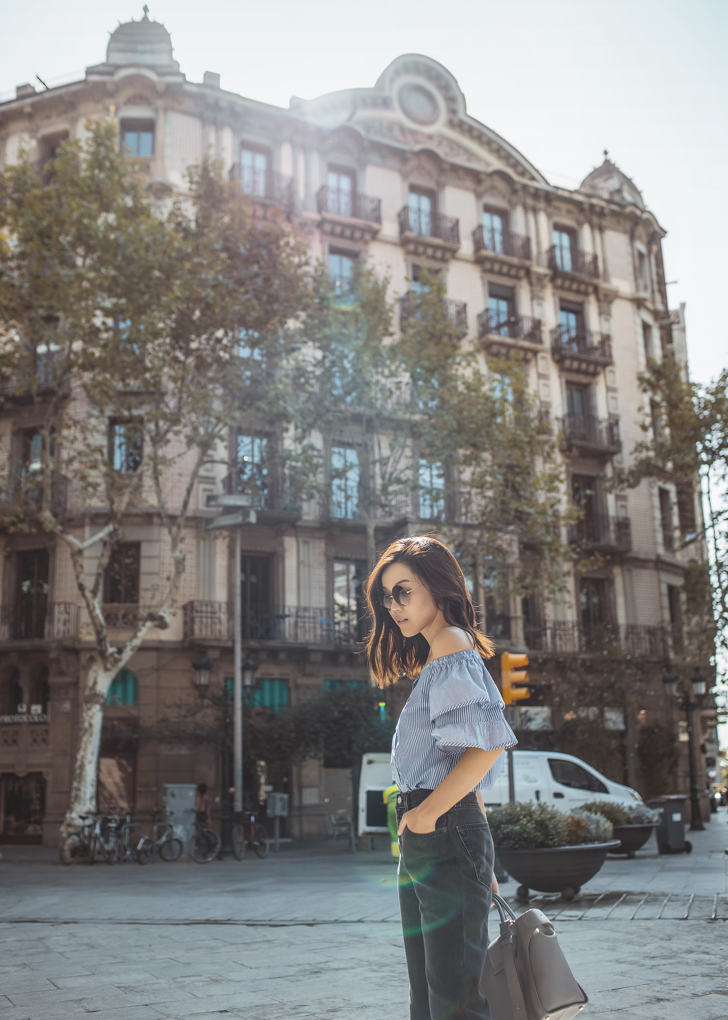 Lifestyle fashion travel blogger Jenny Tsang of Tsangtastic wearing off shoulder ruffle sleeve top and re/done levis jeans and roger vivier leather bag in Barcelona Spain.