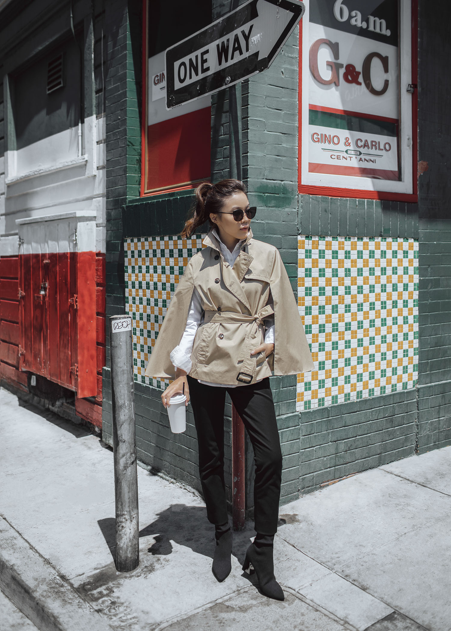 Street style fashion blogger influencer Jenny Tsang of Tsangtastic wearing trench cape white shirt black straight pant sock boots in San Francisco California 